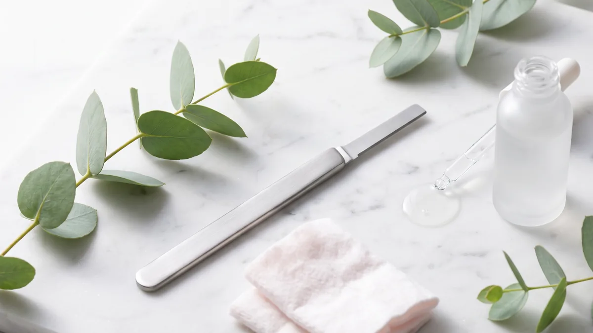 Dermaplaning viso: lama monouso inclinata a 45 gradi sulla guancia durante un trattamento di esfoliazione meccanica