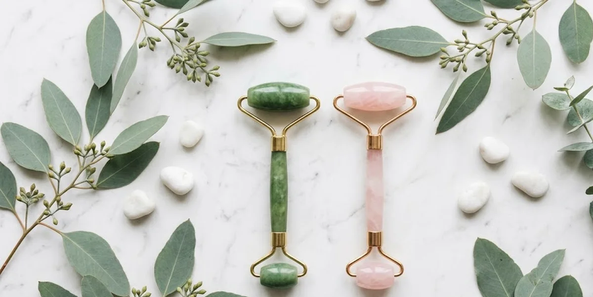 Rullo di giada verde su superficie di marmo bianco per routine skincare