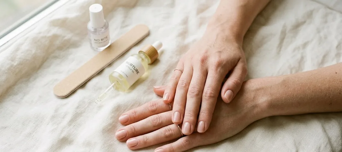 Mani con unghie corte e rovinate dall'onicofagia mentre si applica olio sulle cuticole per farle ricrescere sane